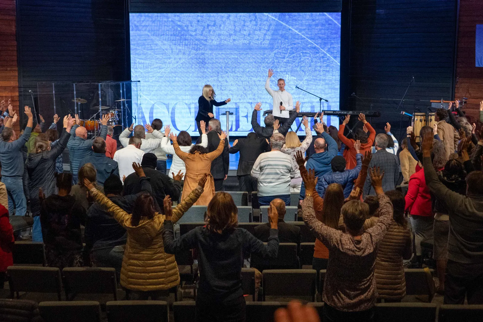 Sons of Faith worship, hands raised across the room